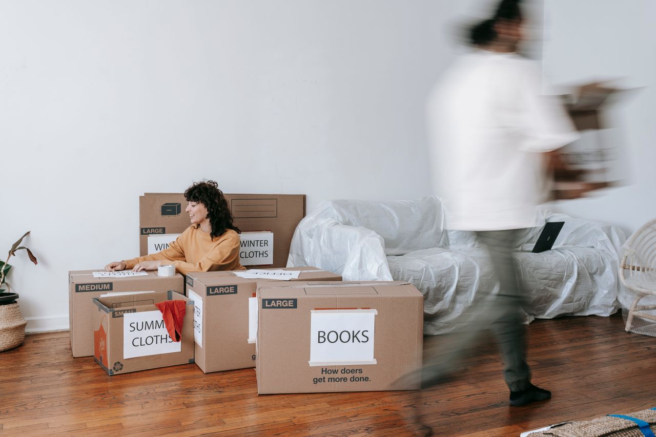 A couple organizing labeled boxes in a minimalist living room as they get ready for moving day.